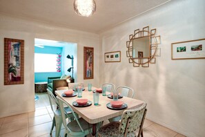 A dining area with a wooden table set for four, surrounded by chairs.