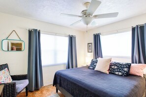 A bedroom with a bed, a chair, a ceiling fan, and a window. - Fun Getaway in the Sun Private Saltwater Pool Yard (Gulfport)