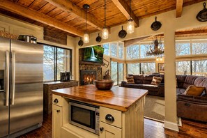 Una cocina amplia con una isla grande, un refrigerador de acero inoxidable y una chimenea de piedra.