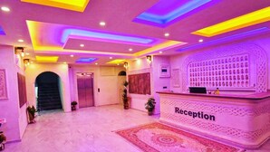 Zona de recepción con mostrador de recepción identificado como "Reception", pared con diseño y suelo de mármol.
