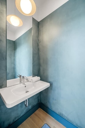 A modern bathroom with a white sink, two pendant lights, and a large mirror. - Xavier at Angels Quarter | Rooftop Terrace (Tampa)