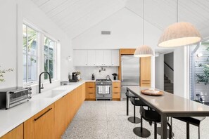 A modern kitchen with a central island, a built-in oven, and a stainless steel refrigerator.