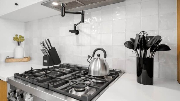 Una cocina moderna con estufa a gas, hervidor y utensileros.