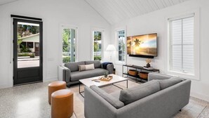 Una sala de estar moderna con un sofá gris, una mesa de centro y un televisor de pantalla plana montado en la pared.