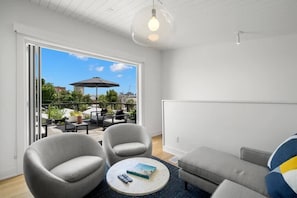 Una sala de estar moderna con un amplio ventanal corredero que da a un patio exterior.