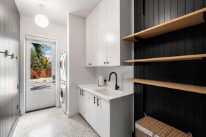 A compact kitchen with white cabinets, a black countertop, and a small sink. - Xavier at Angels Quarter | Rooftop Terrace (Tampa)