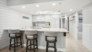 Cozinha com bancada, armários brancos e uma placa com a inscrição 'BEACH HOUSE'.