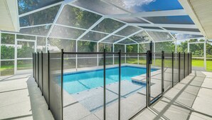 Una piscina coperta con un involucro in vetro e vista sul verde circostante.
