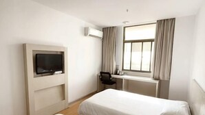 Habitación de hotel con dos camas, televisión, escritorio y ventana con cortinas.