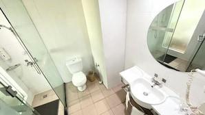 Un baño moderno con cabina de ducha de vidrio, inodoro, lavabo y espejo.