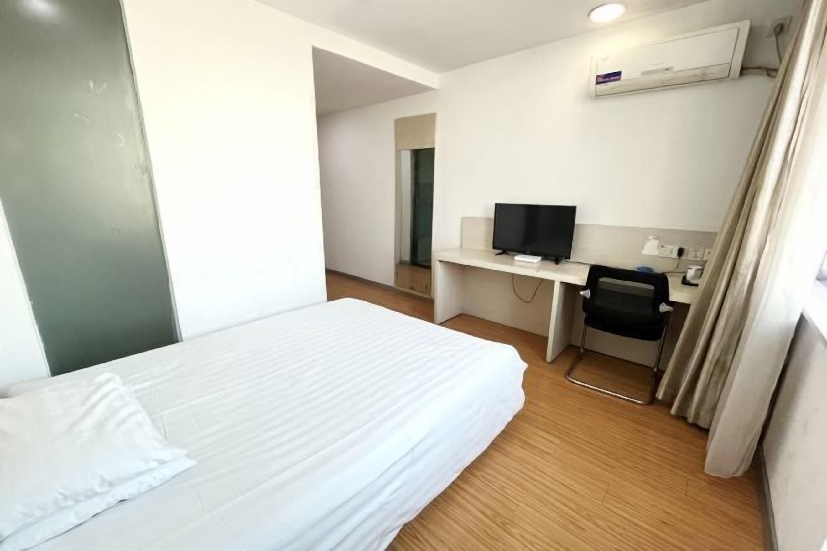 Een hotelkamer met een bed, een bureau met een televisie en een stoel.