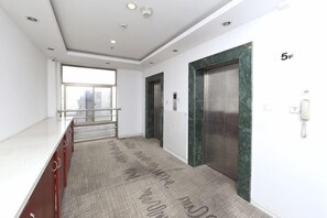 A hallway with a marble elevator, a phone, and a view to the outside. - Suifi Apartment (Wuhu)