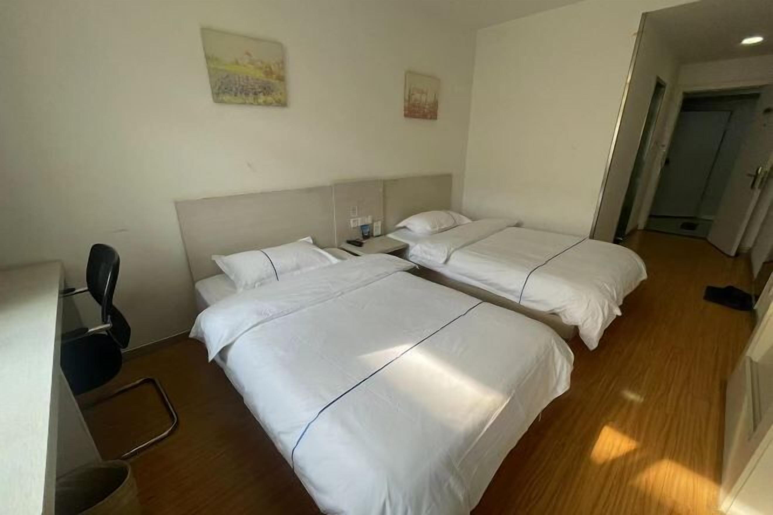 Habitación de hotel con dos camas, un escritorio y una silla.