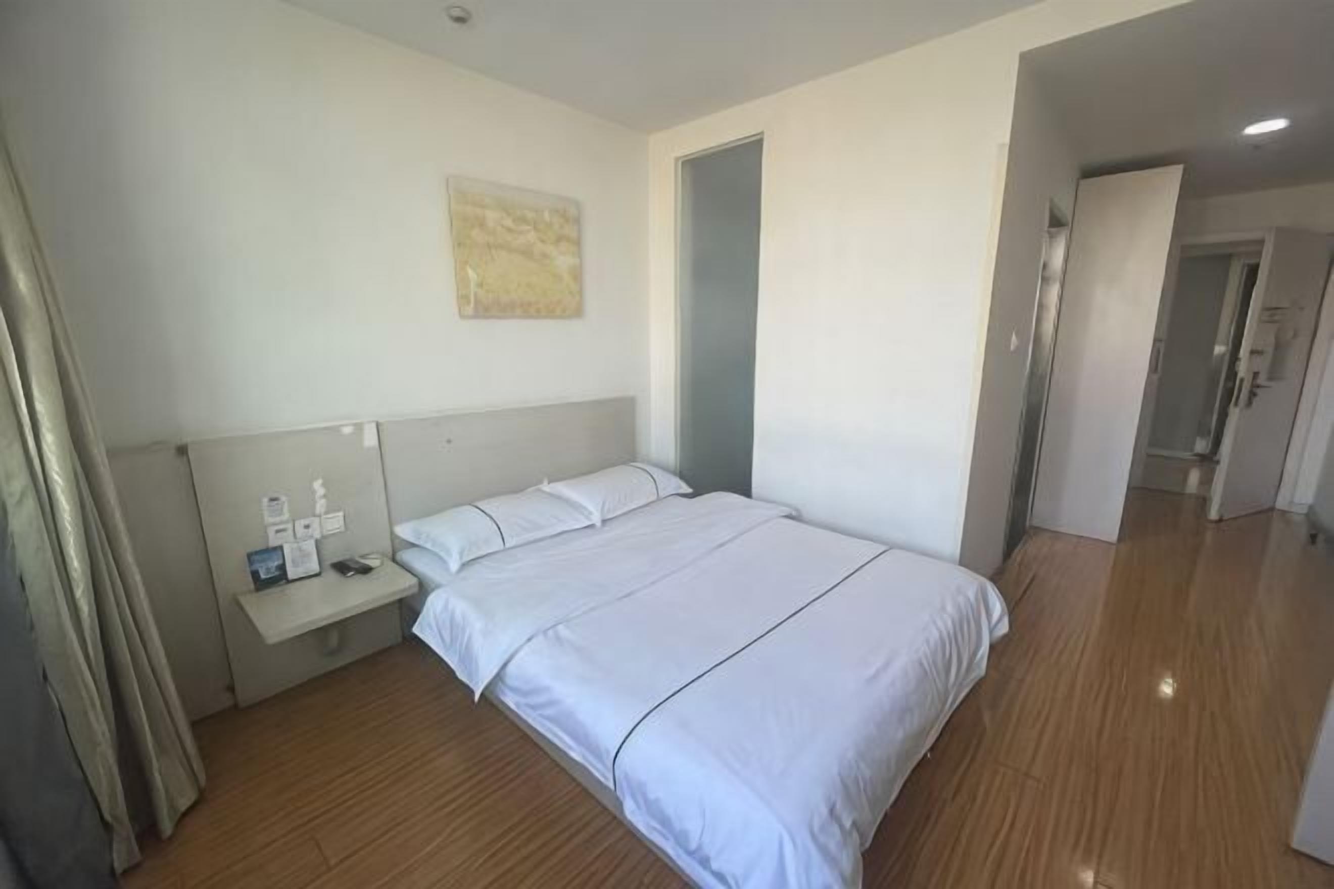 Ein Hotelzimmer mit einem Bett, einem Nachttisch und einer Tür zu einem weiteren Raum.