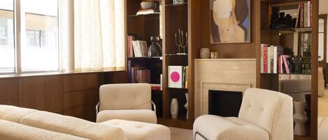 A living room with a fireplace, bookshelves, and two cream-colored sofas.