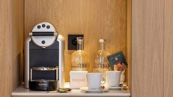 Un minibar con una cafetera Nespresso, dos botellas de vino, una tarjeta y dos tazas blancas con el logotipo de Nespresso.