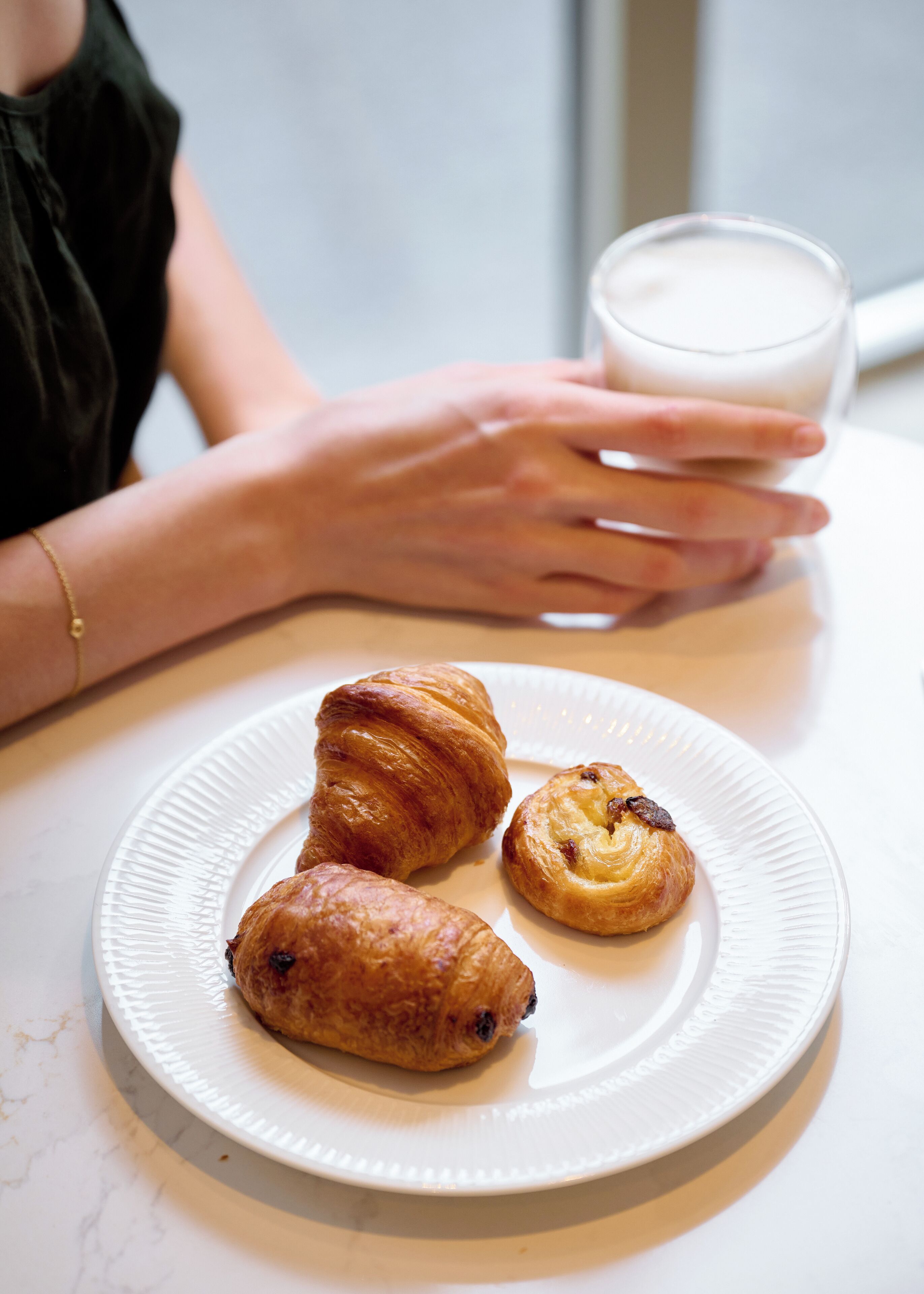 Une assiette avec trois pâtisseries et un verre de lait, posée sur une table.