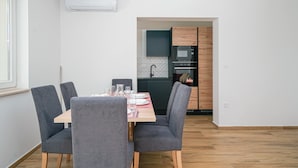 Une cuisine moderne équipée d’un four à micro-ondes, d’un four et d’un évier. Un coin repas avec une table et des chaises est également disponible.