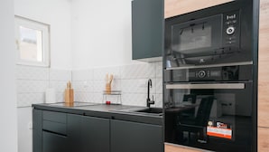 Une cuisine moderne avec des meubles de rangement noirs, un four à micro-ondes et un four encastré.