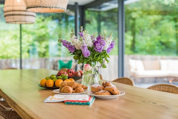 A wooden table with a floral centerpiece, fruits, and pastries.