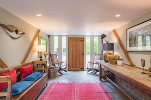 A cozy room with a wooden bench, a red rug, and a wooden door.