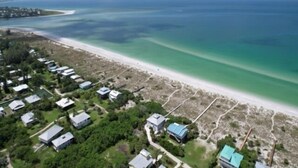 An aerial view of a coastal area with a beach and a cluster of houses. - Welcome to THE HIVE. A hub for peace and relaxation. DIRECT GULF views (Placida)