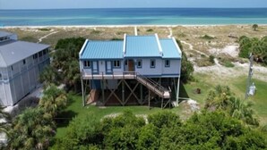 A two-story house with a blue roof, a covered porch, and a staircase leading to a deck. - Welcome to THE HIVE. A hub for peace and relaxation. DIRECT GULF views (Placida)
