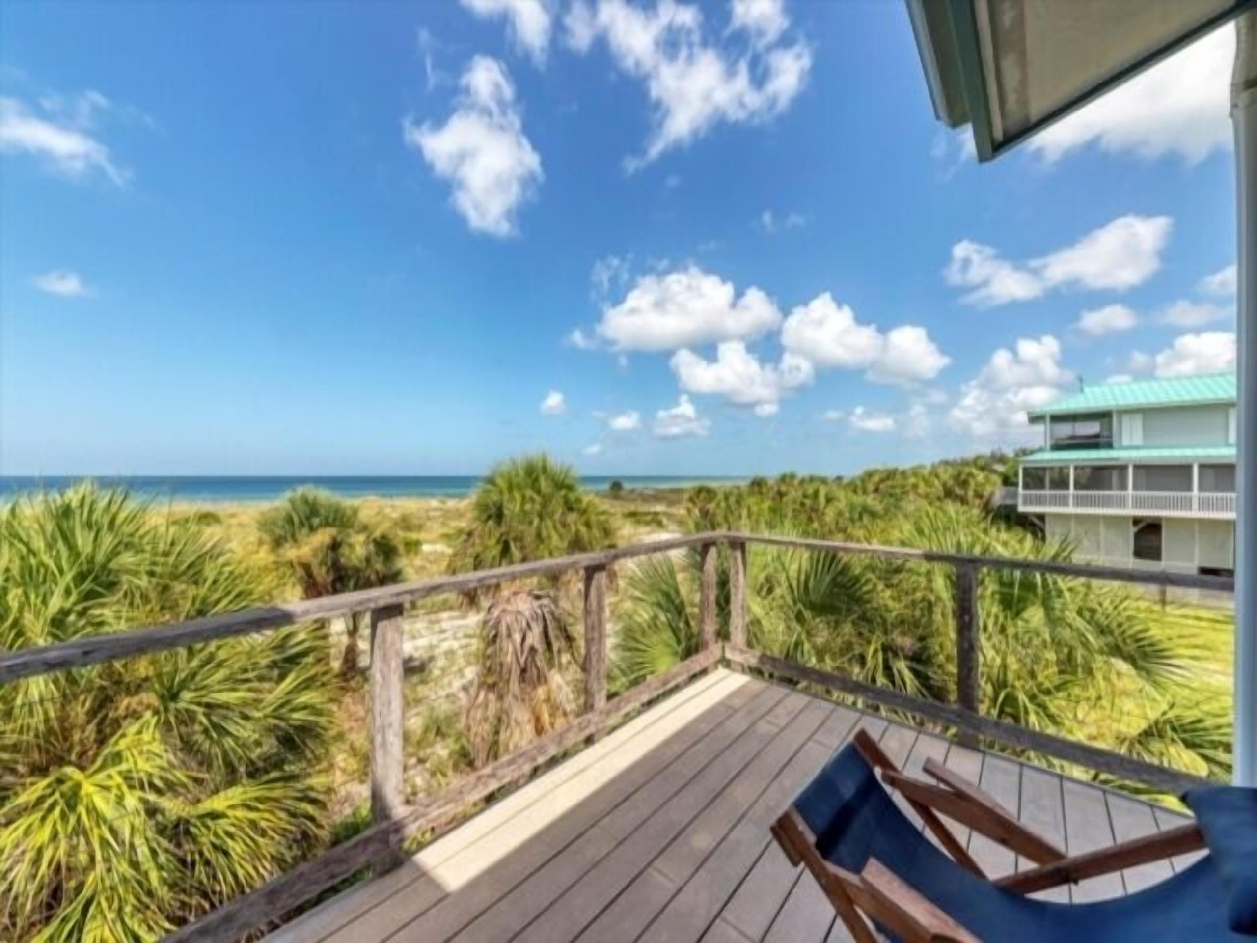 A wooden deck with a view of the ocean and a building in the background.