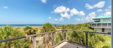 A wooden deck with a view of the ocean and a building in the background.