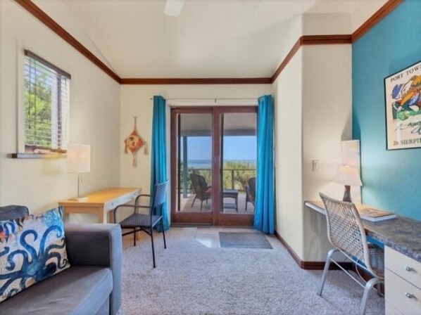 A room with a sofa, a desk, a chair, and a view through a glass door to an outdoor area. - Welcome to THE HIVE. A hub for peace and relaxation. DIRECT GULF views (Placida)