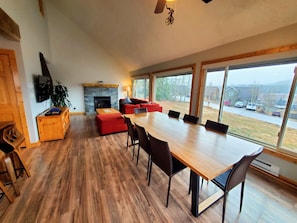 Ein geräumiger Wohnbereich mit einem großen Holzesstisch, roten Sofas und einem Steinkamin.
