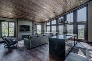 Enjoy expansive views of the surrounding landscape from the large windows in this living area, featuring a comfortable sofa and coffee table.