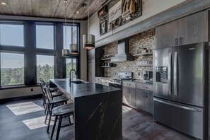 Una cocina moderna con una isla grande, electrodomésticos de acero inoxidable y una pared decorativa de ladrillo.
