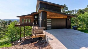 Une maison moderne dotée d’une terrasse en bois, d’un garage et offrant une vue sur les montagnes.