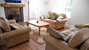Een woonkamer met twee beige banken, een houten salontafel en een open haard.