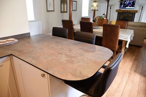 A kitchen with a large island, dining table, and chairs. There is a television in the background and a fireplace. - The Stables -  Retreat Group (Pitlochry)