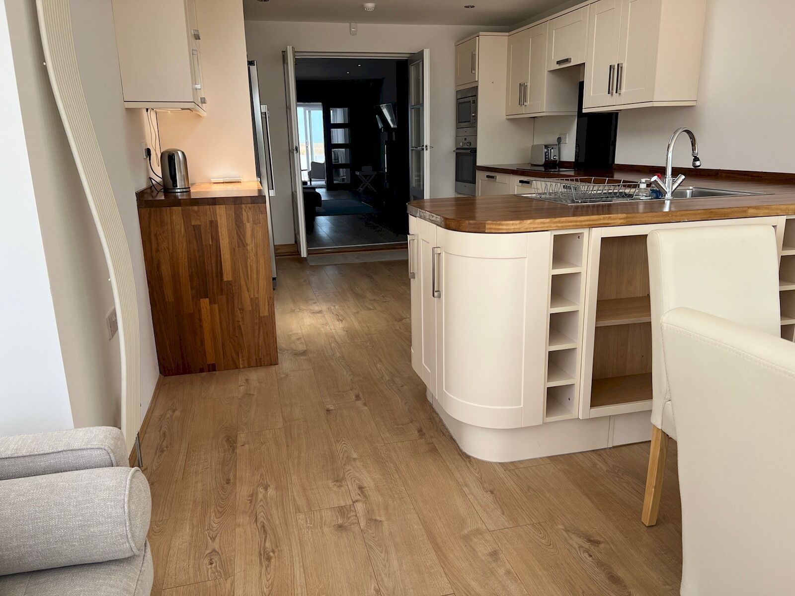 Una cocina moderna con armarios blancos, encimera de madera y un lavamanos integrado.