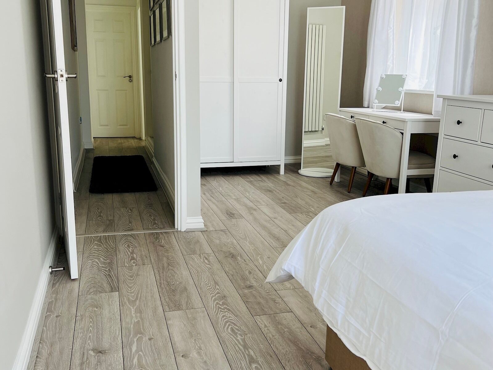 A bedroom with a bed, a desk, and a wardrobe.
