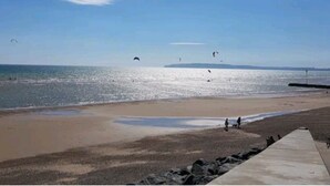 Una playa con un paseo marítimo de concreto y un litoral rocoso.