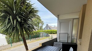 Ein Balkon mit Tisch und Stühlen, einer Palme und Blick auf ein Haus und eine Straße.