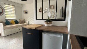 Eine kompakte Küche mit einem integrierten Kühlschrank, einer Holz Arbeitsplatte und einem großen Spiegel über dem Spülbecken.