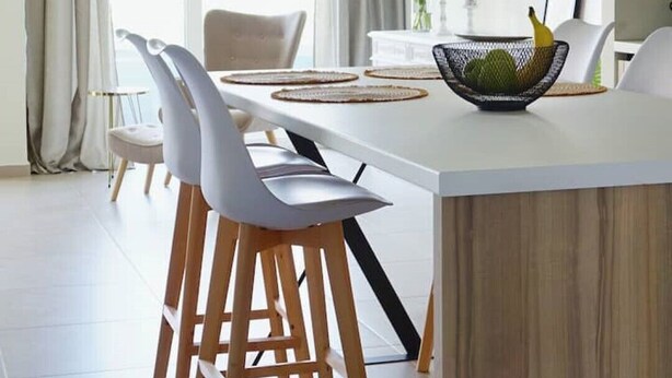 A modern kitchen with a central island, white chairs, and a hanging light fixture. - Luxurious, modern, cozy apartment in Heraklion (Heraklion)