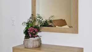 A wooden console table with a mirror above it, a potted plant, and a cushion on the table. - Luxurious, modern, cozy apartment in Heraklion (Heraklion)