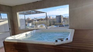 Ein Whirlpool in einem Zimmer mit großen Fenstern und Blick auf die Stadt.