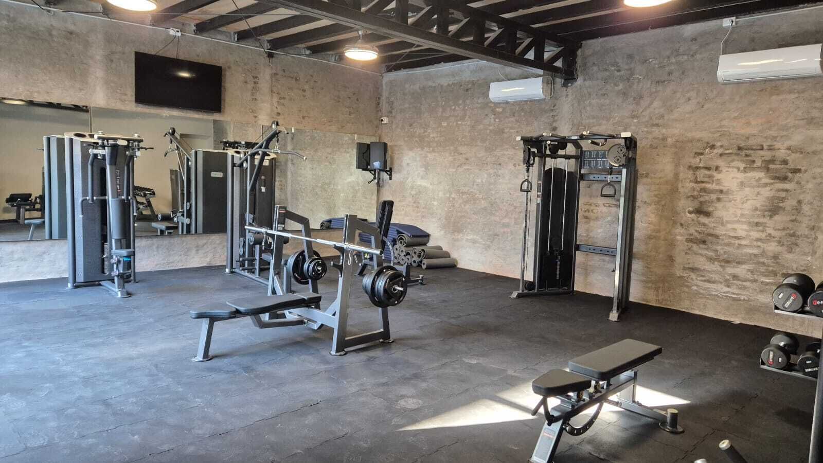 Ein Fitnessraum mit Gewichte, Bänken und einer Spiegelwand.