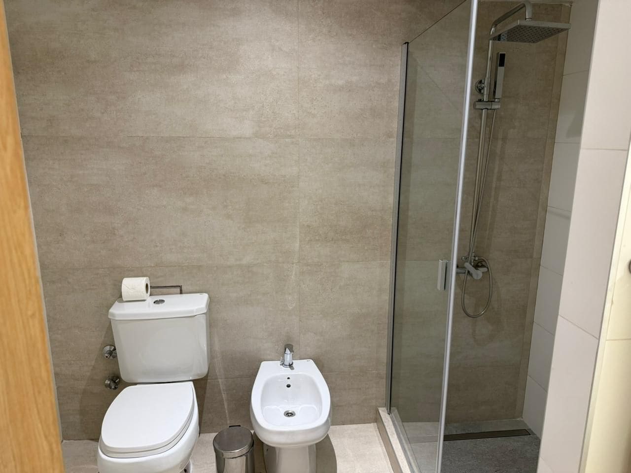 A bathroom with a toilet, bidet, and glass-enclosed shower.