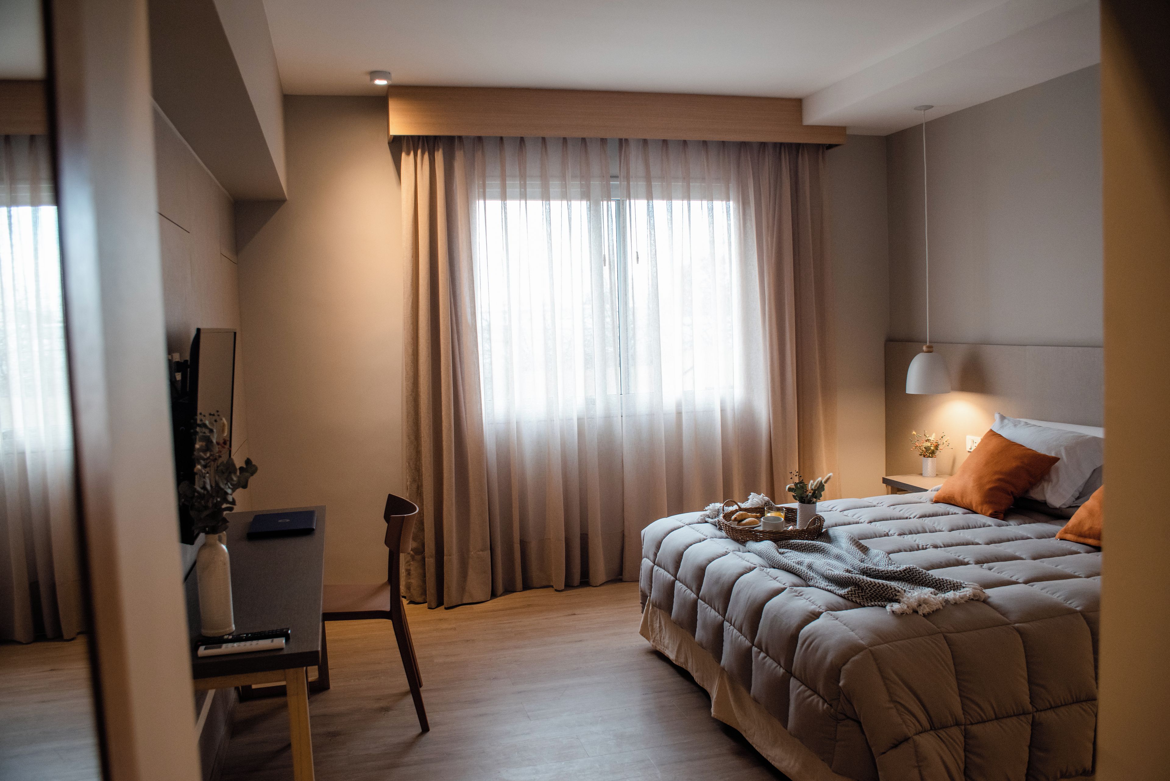 A modern bedroom with a large bed, a desk, and a chair.