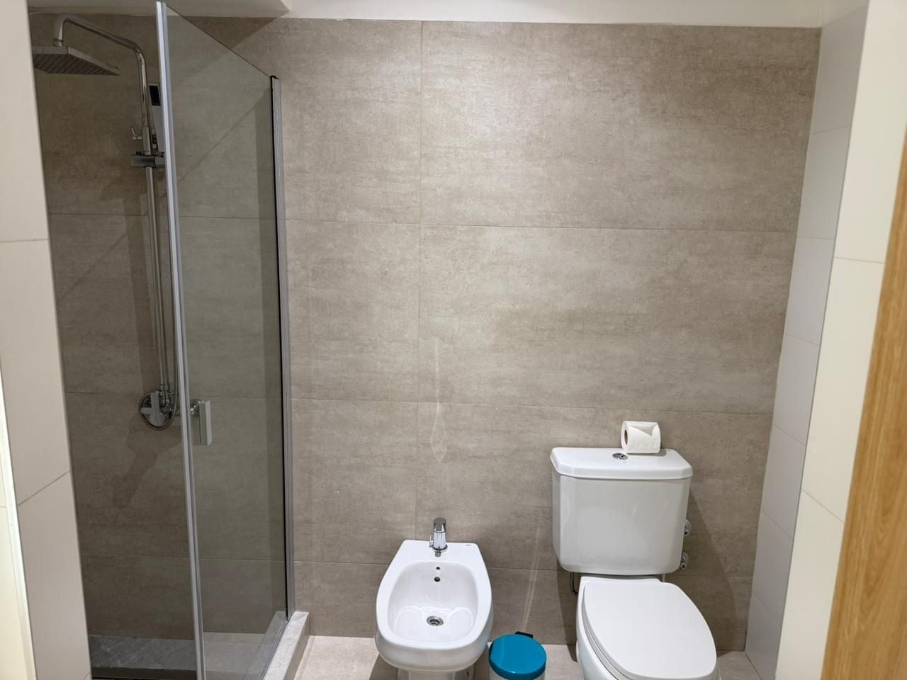 Et badeværelse med brusekabine i glas, et bidet og et toilet.