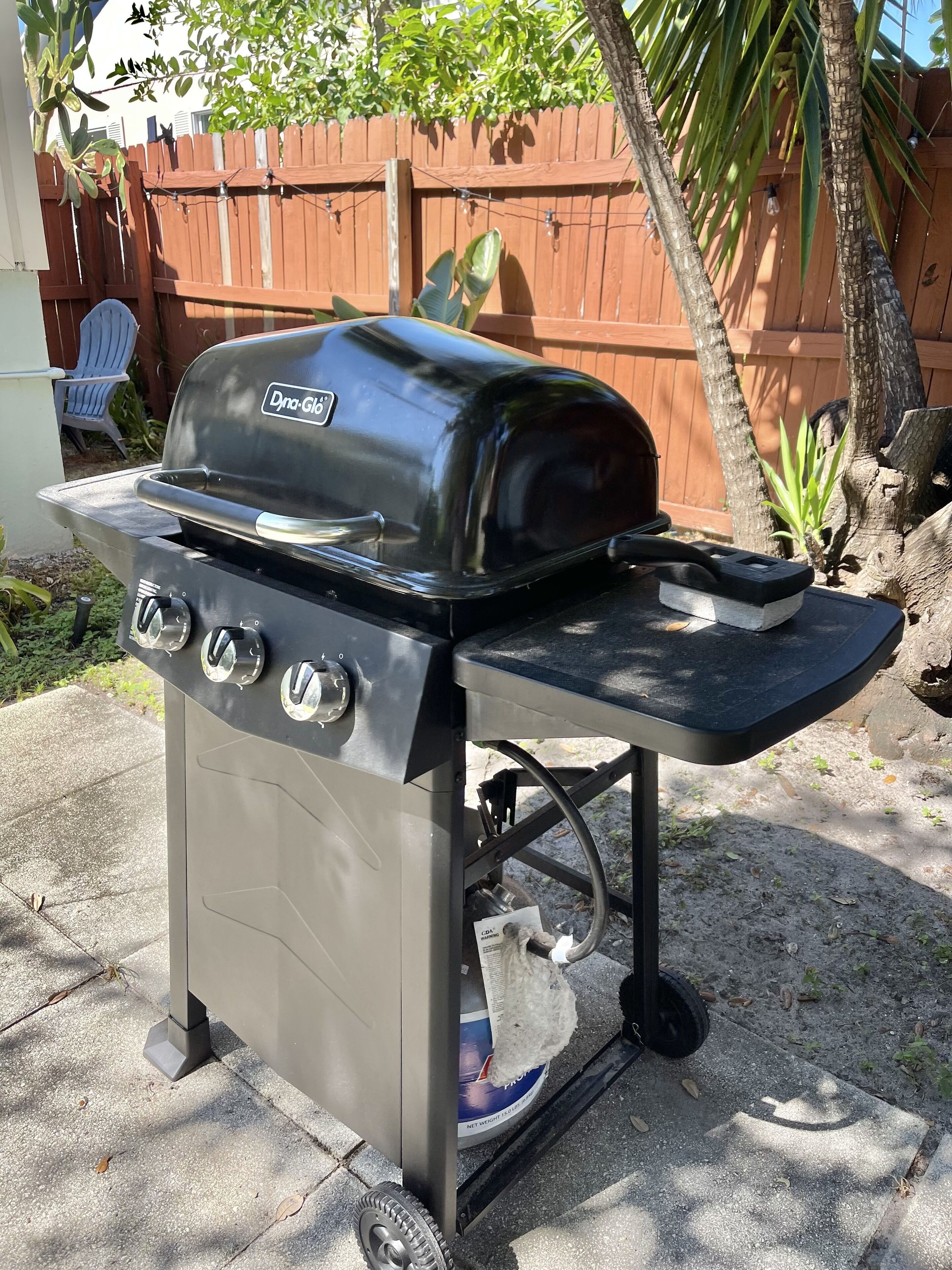 A portable gas grill with a digital display, a side table, and a built-in thermometer.