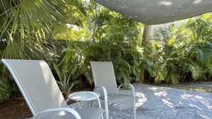 Deux chaises en métal blanc, dotées d’une structure et d’un dossier en métal, sont posées sur un sol à motifs.